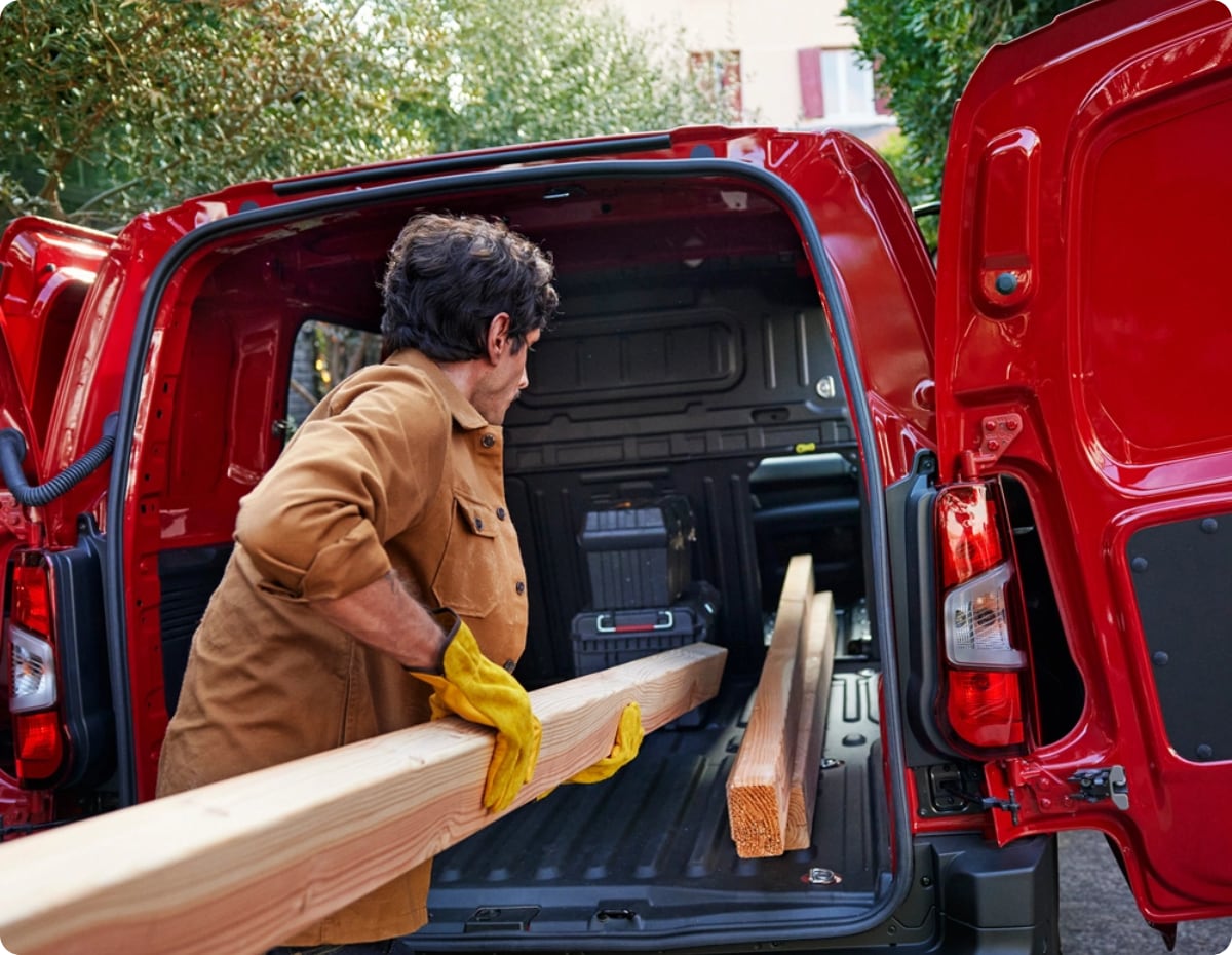Rear three‑quarter exterior view of a red Citroën Jumpy with rear doors open during loading, showing large cargo capacity, practical access and everyday professional use.