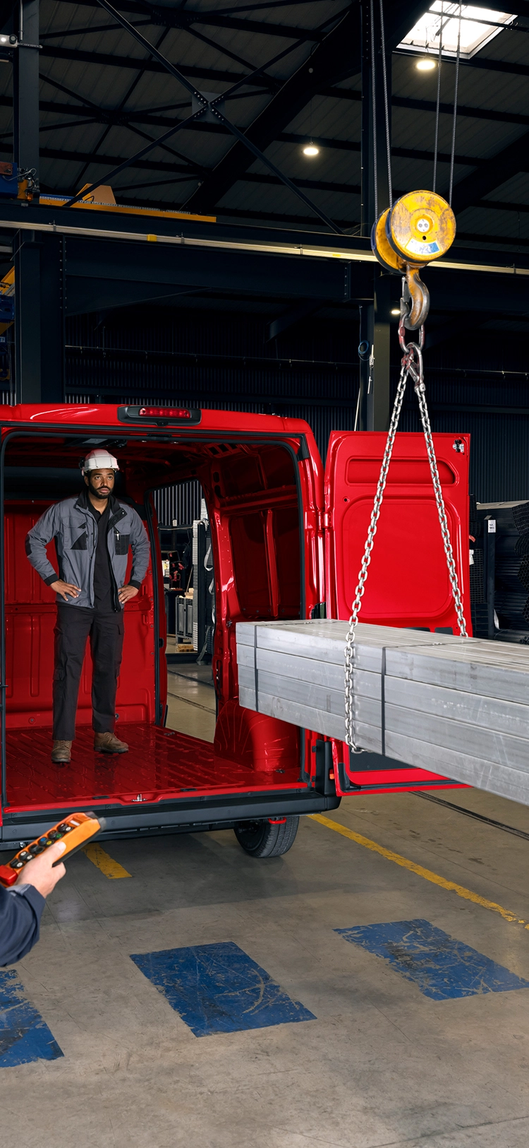 Vista posteriore di Citroën Jumper rossa caricata con travi metalliche in un contesto industriale, che mette in risalto il grande volume di carico e la capacità per usi gravosi.