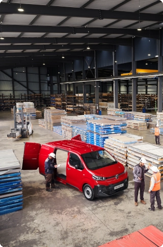 Vista esterna dall’alto di un Citroën Jumpy rosso parcheggiato in un magazzino industriale, che mette in risalto dimensioni esterne compatte, ampia capacità di carico e praticità professionale.