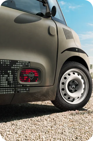 Primo piano della ruota della Citroën Ami Outdoor con cerchi in acciaio bianchi, una microcar elettrica compatta per la mobilità quotidiana