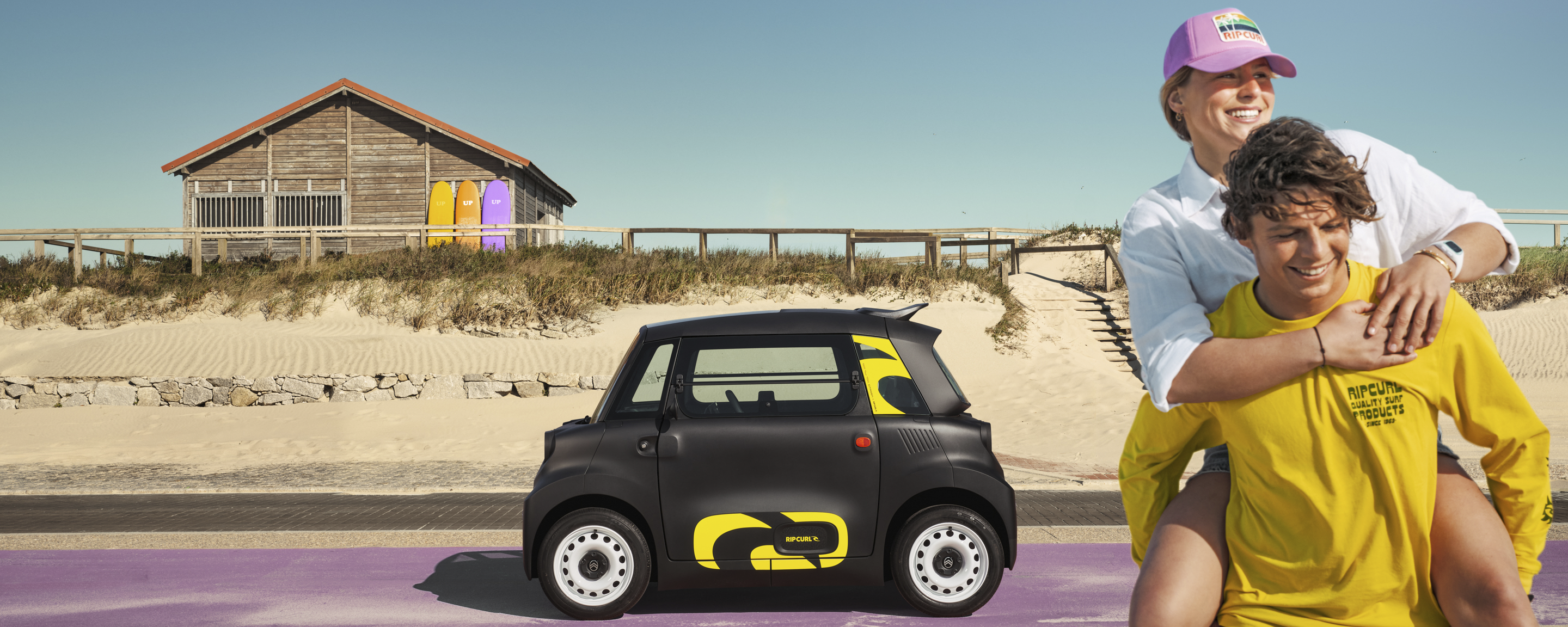 Vista lifestyle laterale Citroën Ami x Rip Curl elettrica senza patente, Citroën Ami libertà sul mare per mobilità urbana elettrica