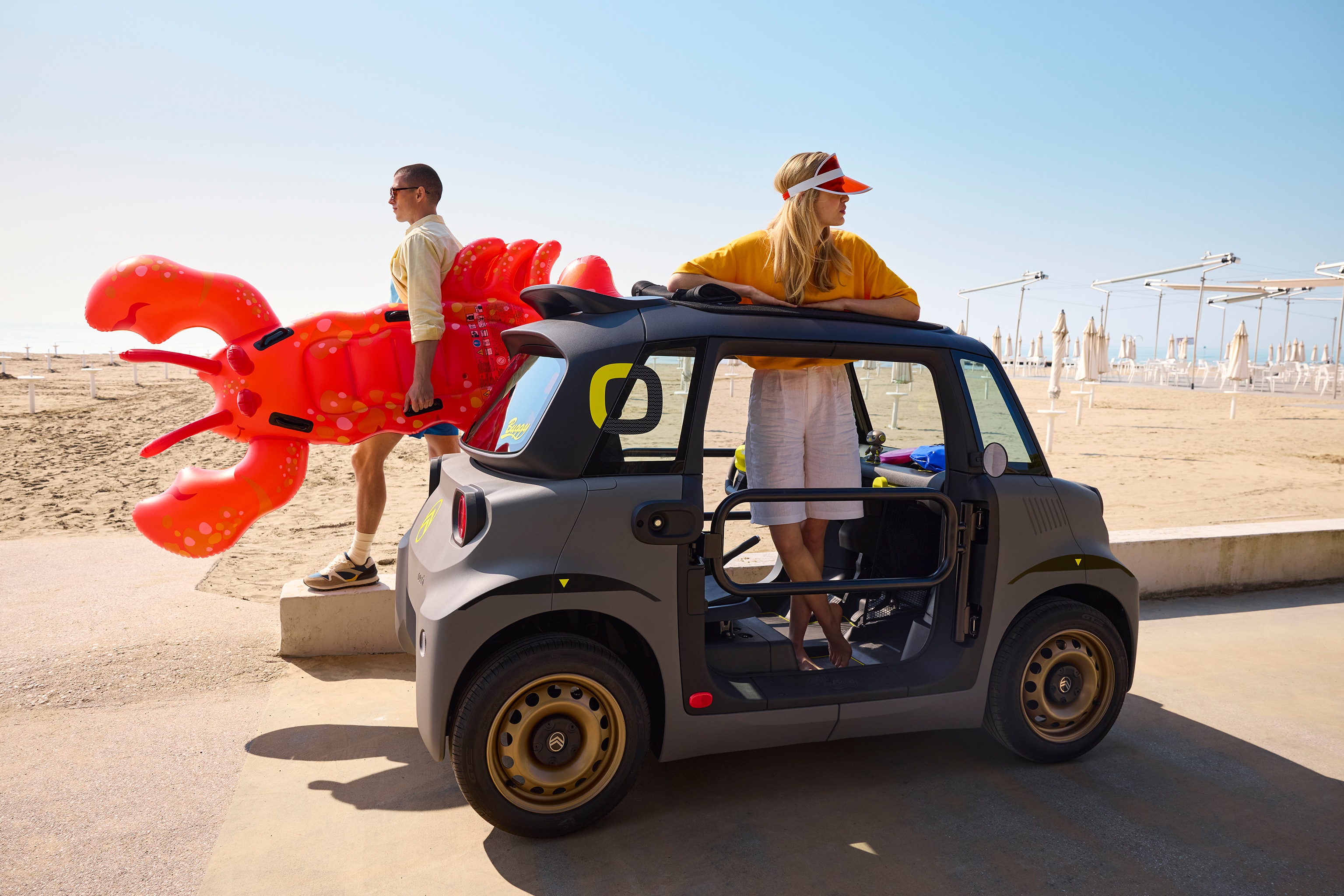 Vista laterale in spiaggia di Citroën Ami Buggy che mette in evidenza un design elettrico compatto e aperto, sicuro e affidabile, ideale per godersi la libertà dell’estate.