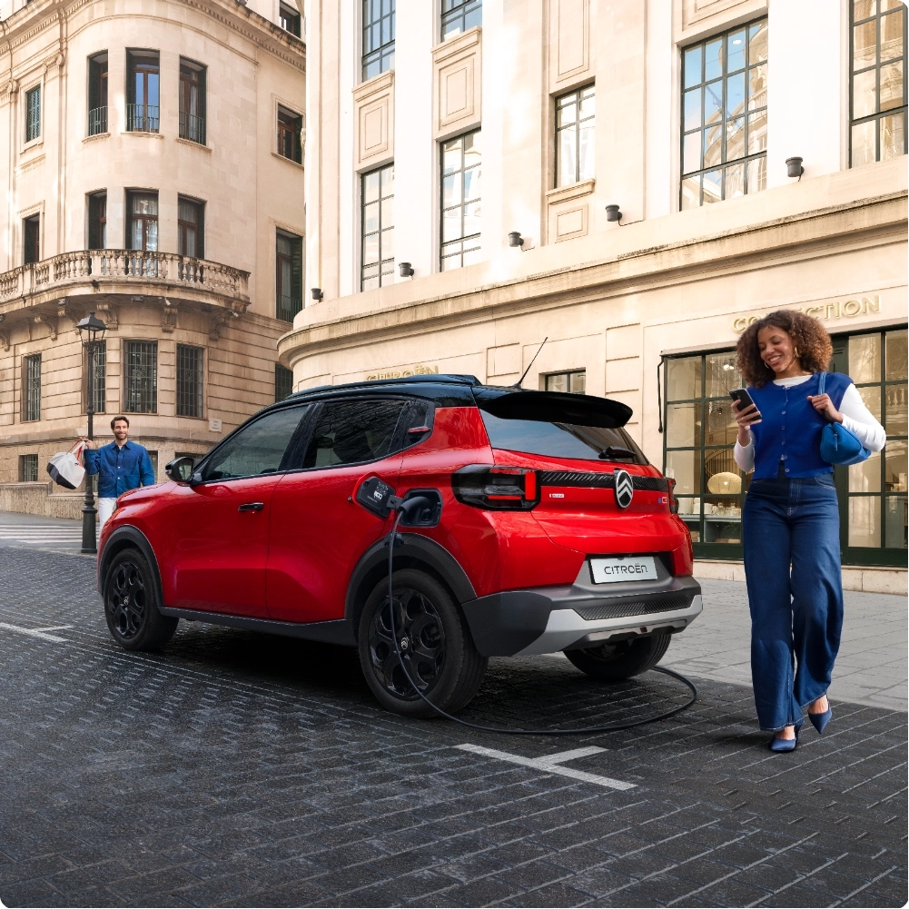 Vista anteriore in marcia di Citroën ë-C3 che mostra la sua agilità nell'ambiente urbano, per una mobilità cittadina sicura, efficiente e accessibile.