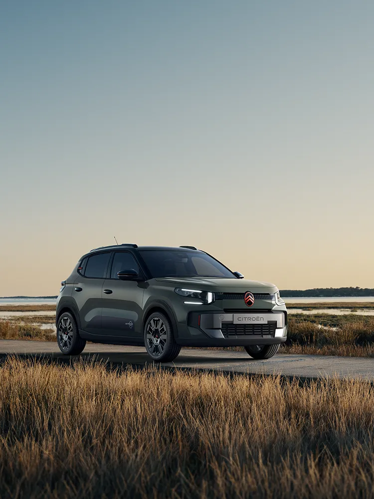 Vista anteriore a tre quarti di Citroën C3 Outdoor con firma luminosa a LED, che mostra l'Advanced Comfort di questo SUV accanto a zone umide costiere