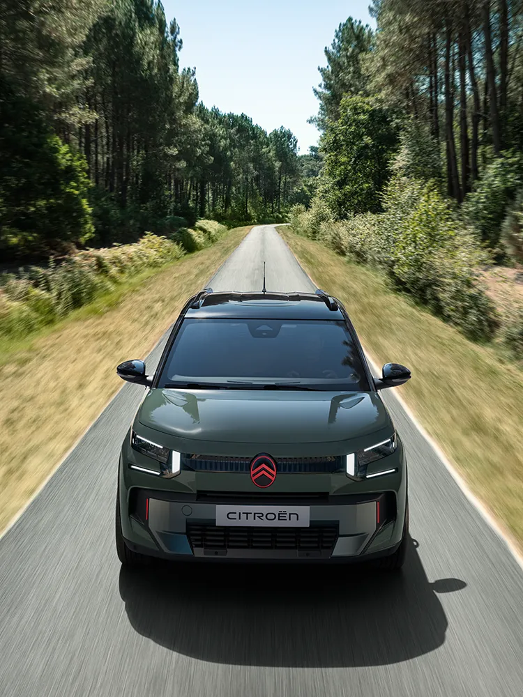 Vista anteriore dall'alto di Citroën C3 Outdoor, con firma luminosa a LED, che mostra questo SUV compatto Advanced Comfort su una strada nel bosco