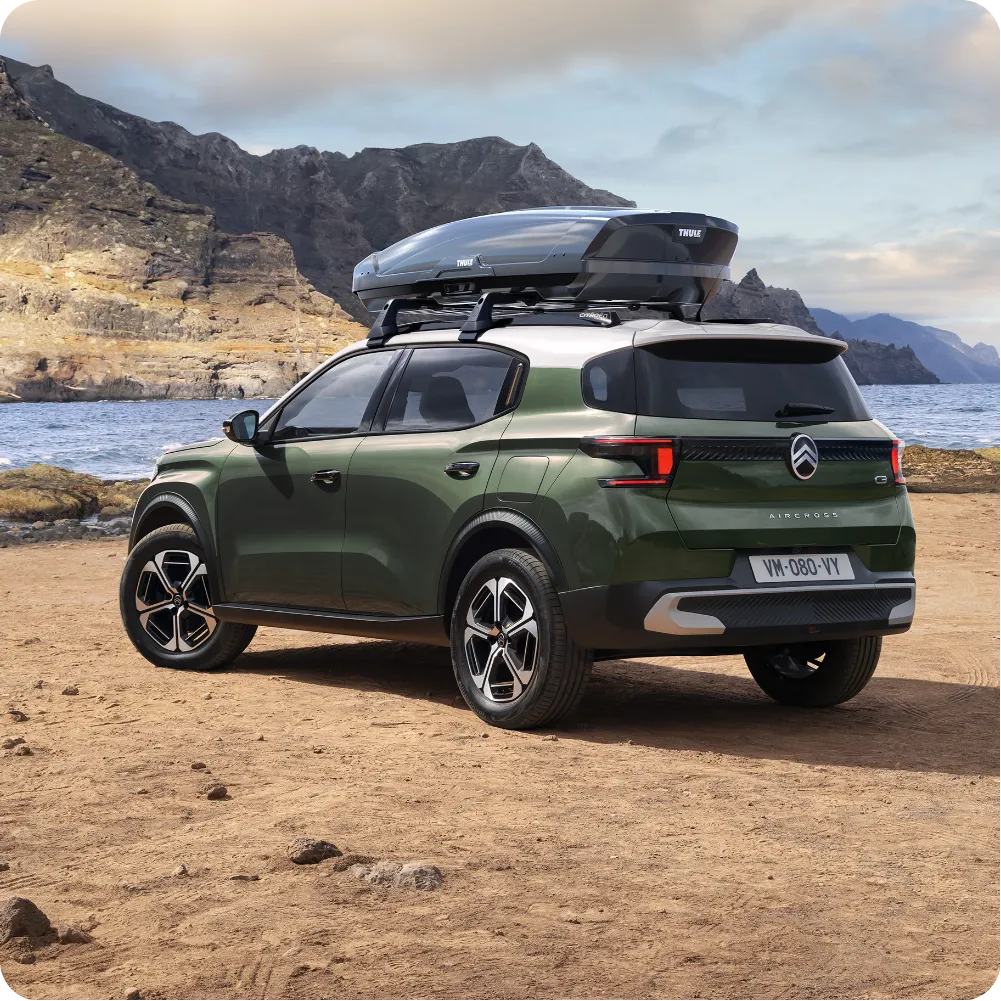 Outdoor view di Citroën ë-C3 Aircross con barre al tetto e roof box per una capacità di viaggio versatile, spaziosa e accessibile.