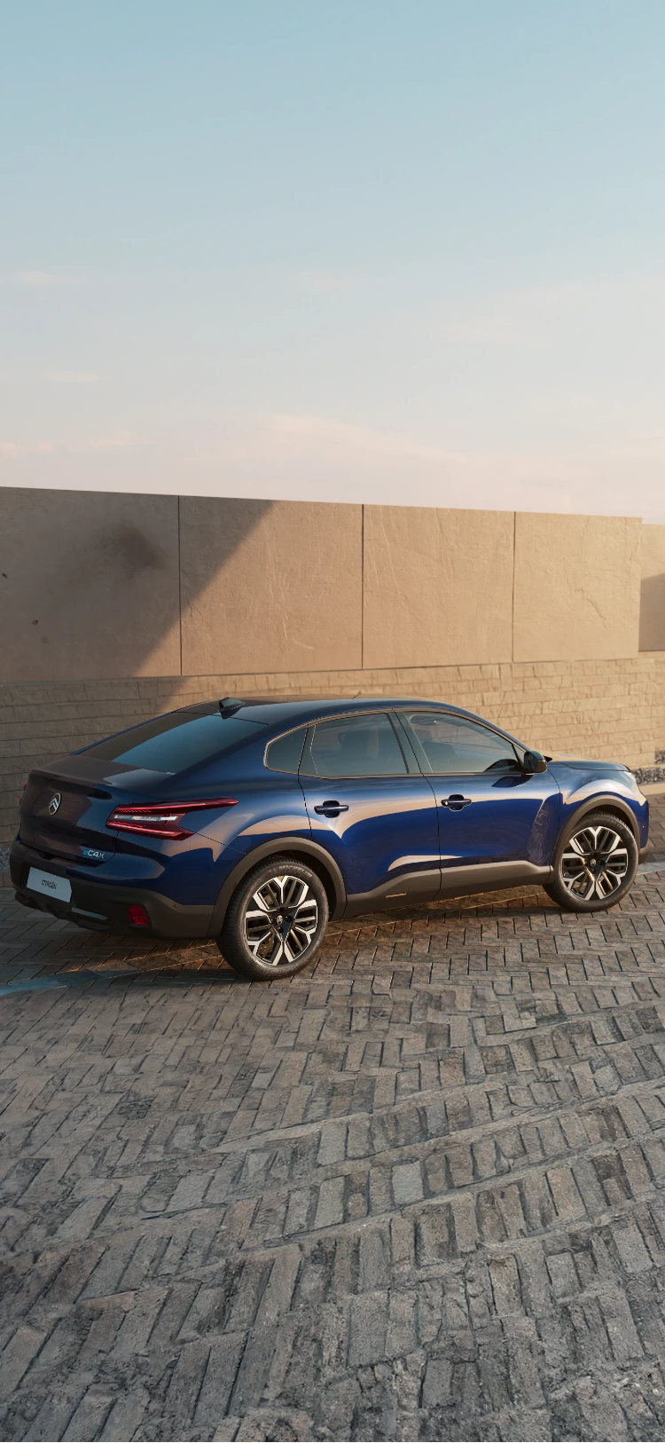 Side view of the Citroën C4 X driving along the coast at sunset, highlighting its sleek profile