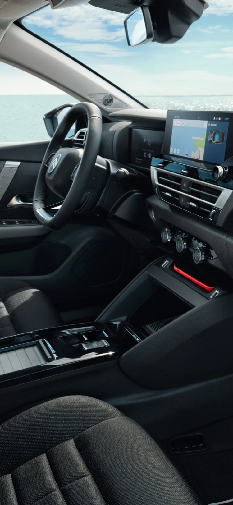 Front cabin of the Citroën C4 X with dashboard and seats shown against a seaside backdrop