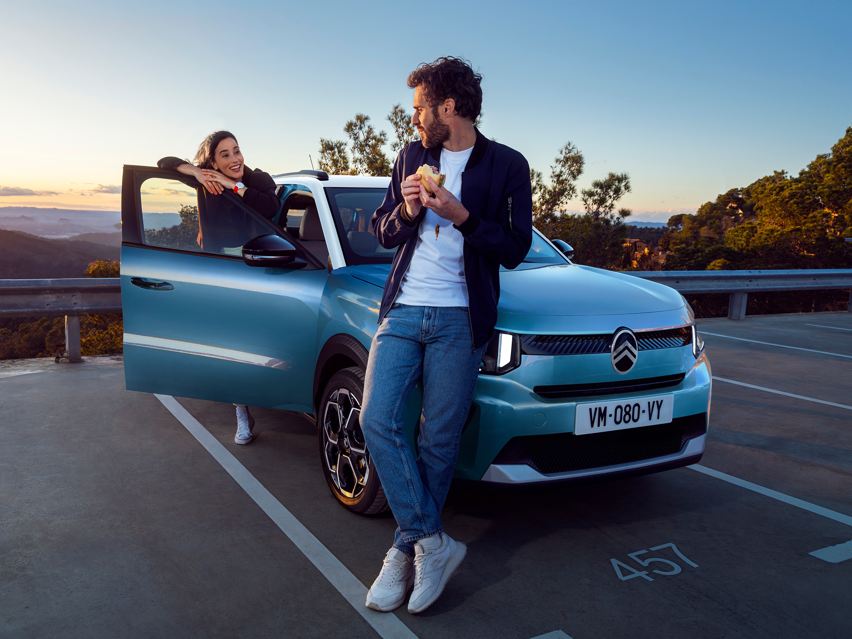 Vista anteriore di tre quarti di Citroën ë-C3 che mette in evidenza un momento di pausa rilassato, per una mobilità quotidiana fluida e accessibile.