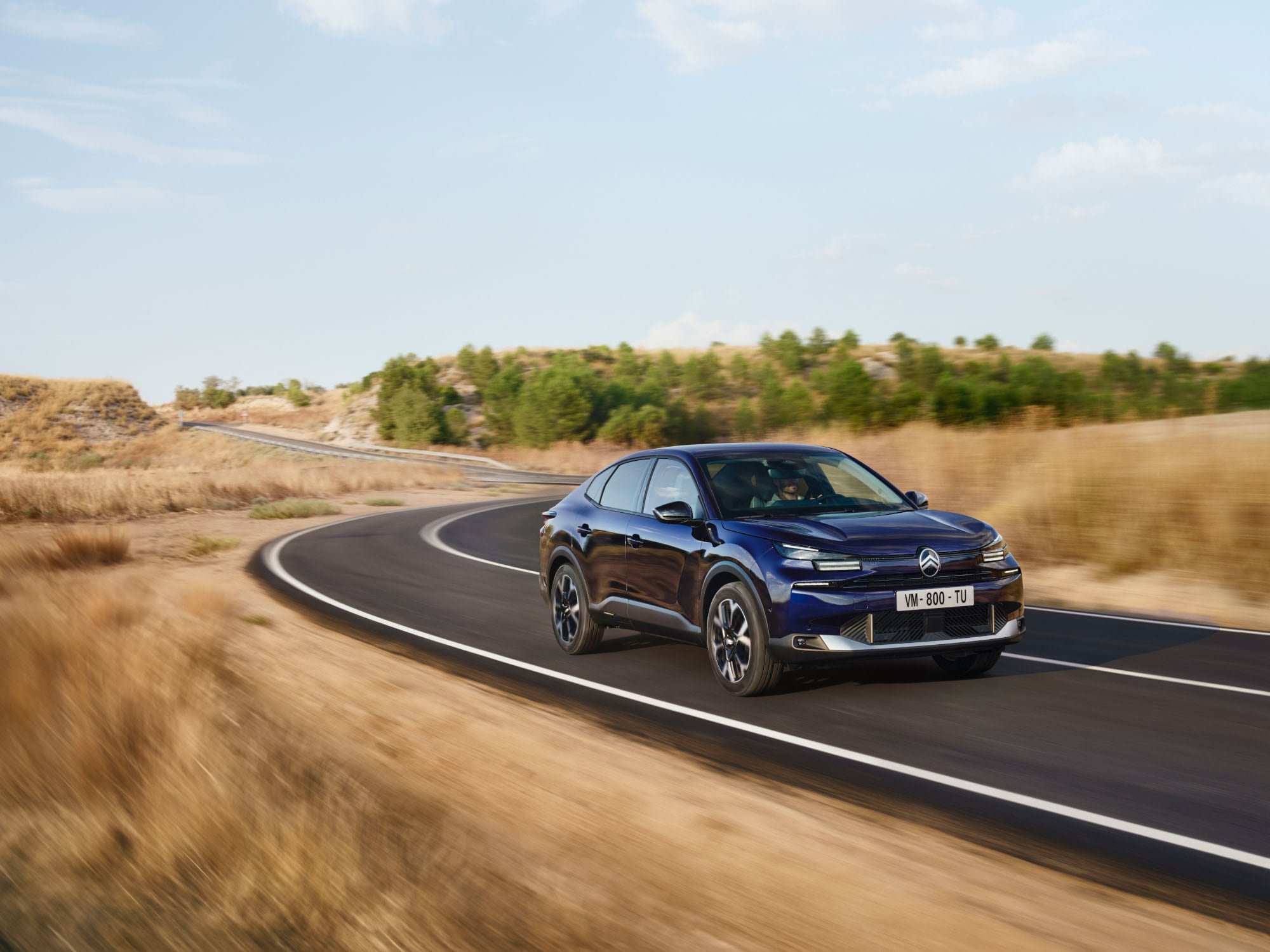 Vista anteriore di tre quarti in movimento della Citroën ë-C4 X che mostra il design fastback agile per una mobilità sicura e accessibile