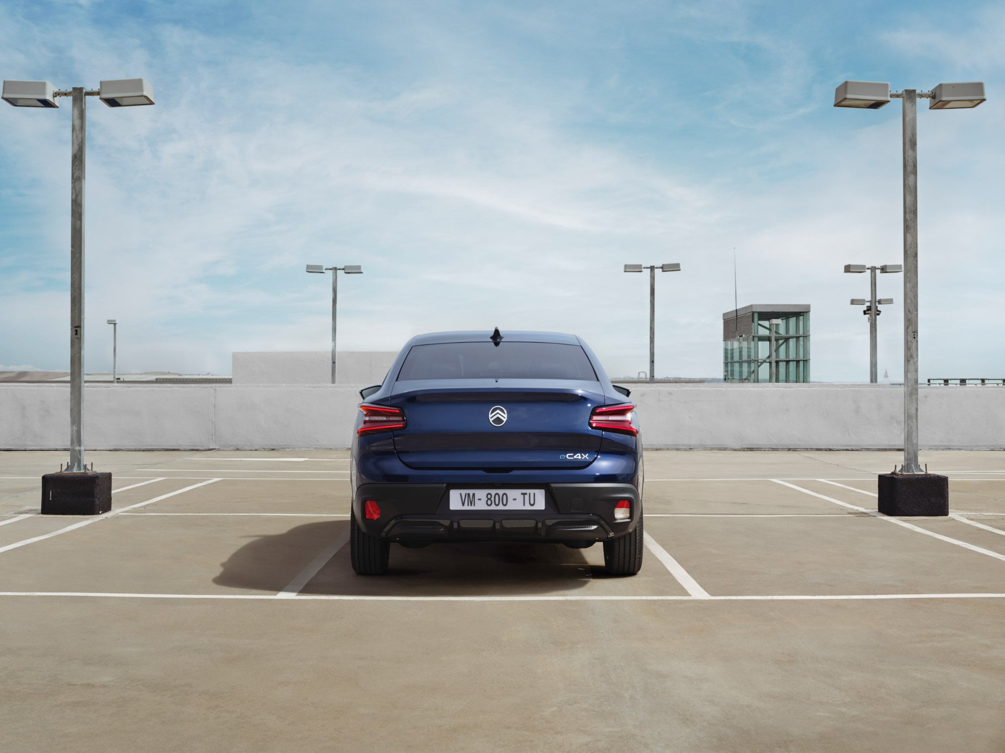 Vista posteriore della Citroën ë-C4 X in un parcheggio sul tetto, che mette in risalto il design fastback distintivo per una mobilità elegante e accessibile